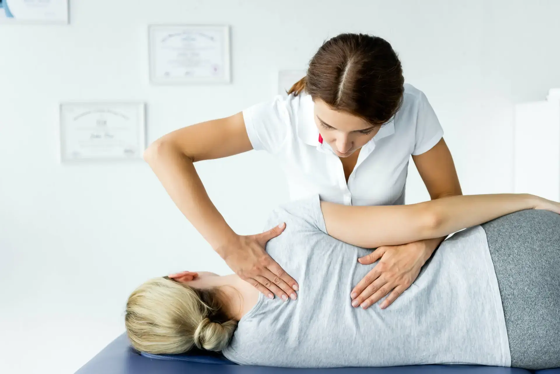 picture of attractive chiropractor touching hand of patient in grey t shirt